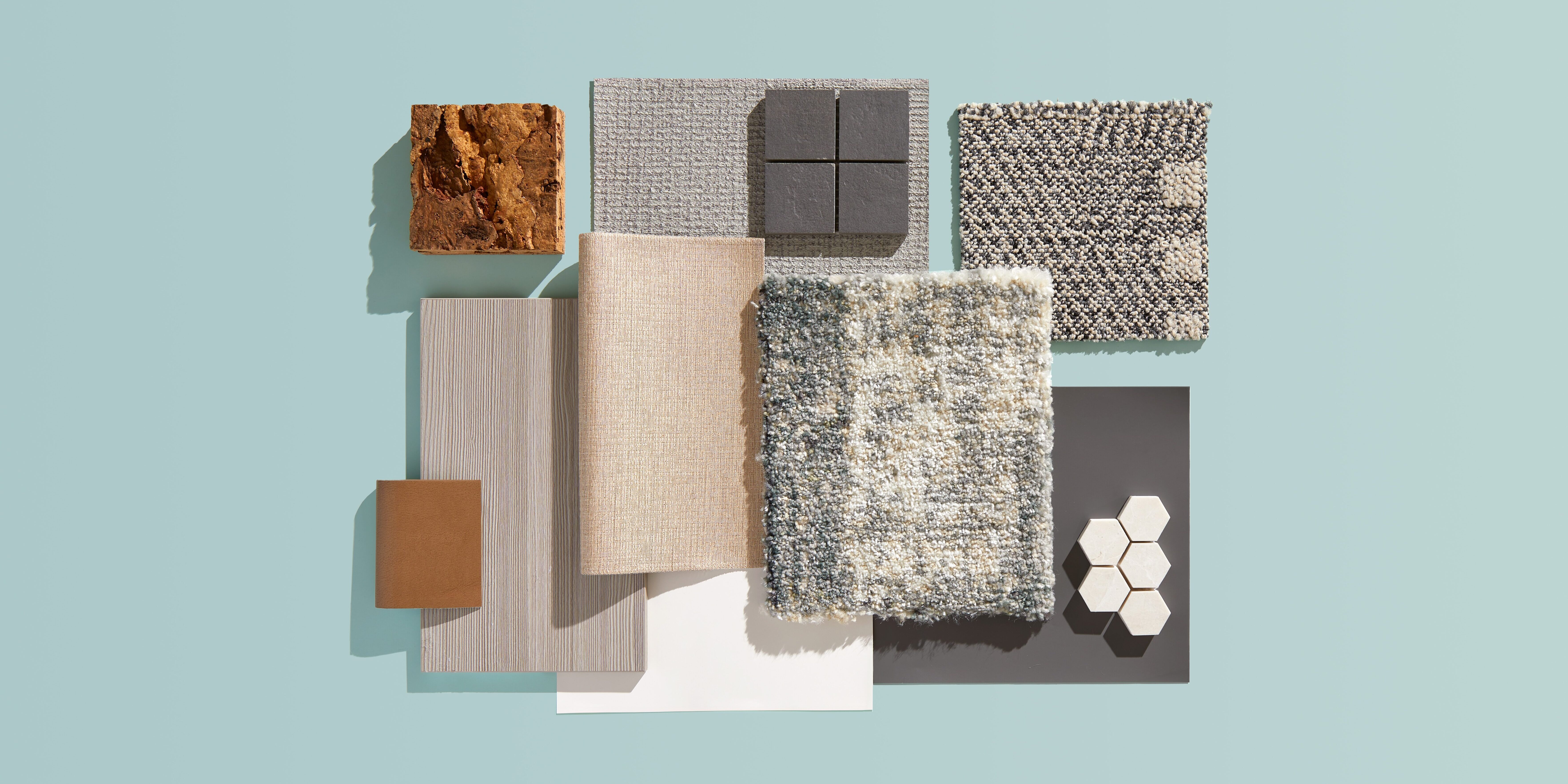 Flatlay of neutral materials highlighting the idea of refined contrast in shades of gray, beige, and brown on a soft blue background.