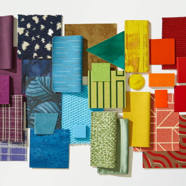 An image showcasing a celebration of color. A flat lay with a variety of material samples ranging from tiles and textiles to wallcoverings and surfaces creating a gradient effect in shades of red, orange, yellow, green, blue, indigo and violet.