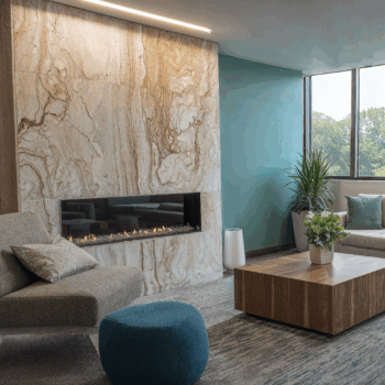 A clinic lounge with a marble fireplace, upholstered furniture, and teal painted walls.