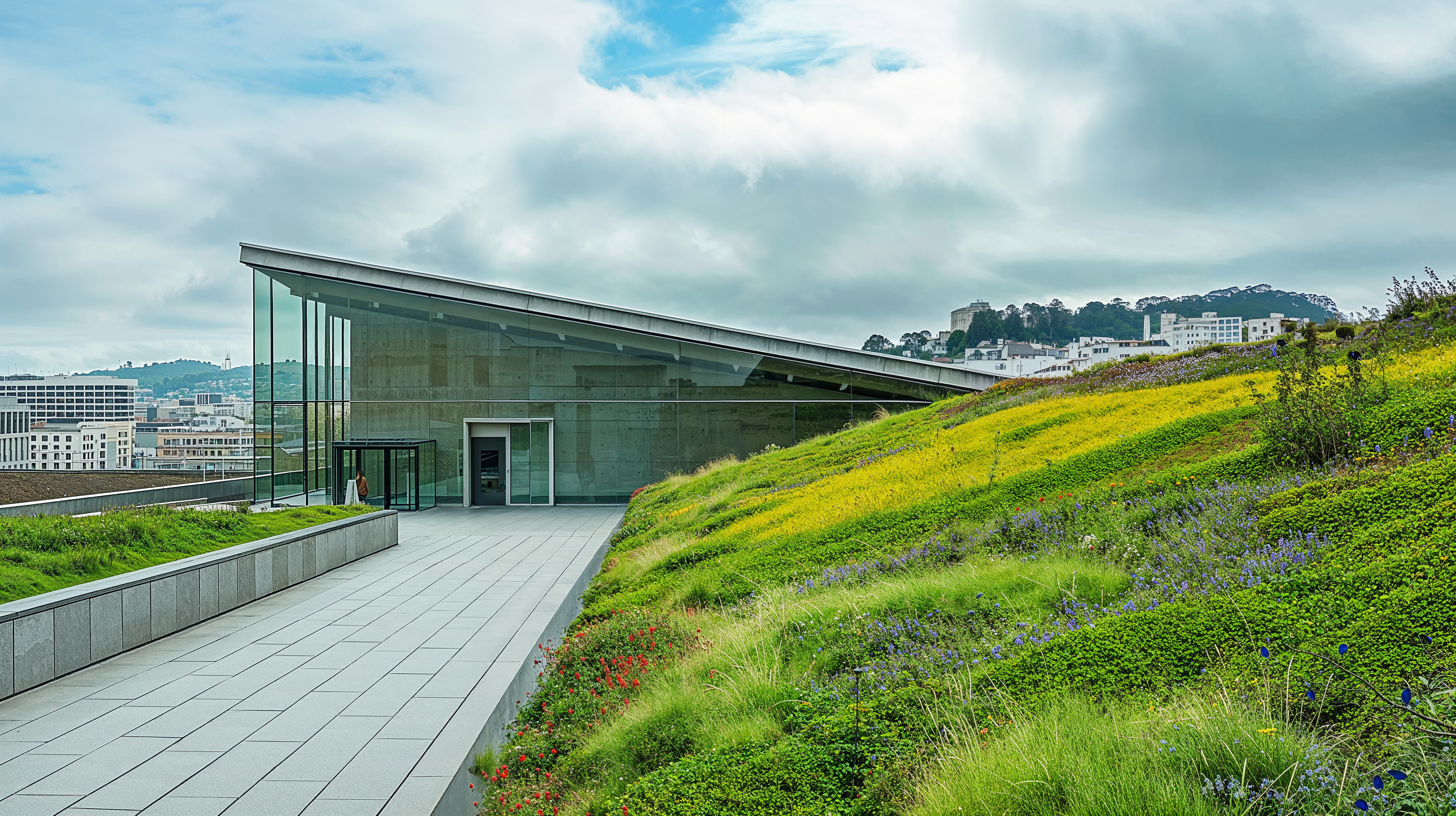 Green roofs and walls on top of an urban building. A walkway surrounded on both sides by concrete and steel retention walls line both sides surrounded by a variety of plants and flowers.