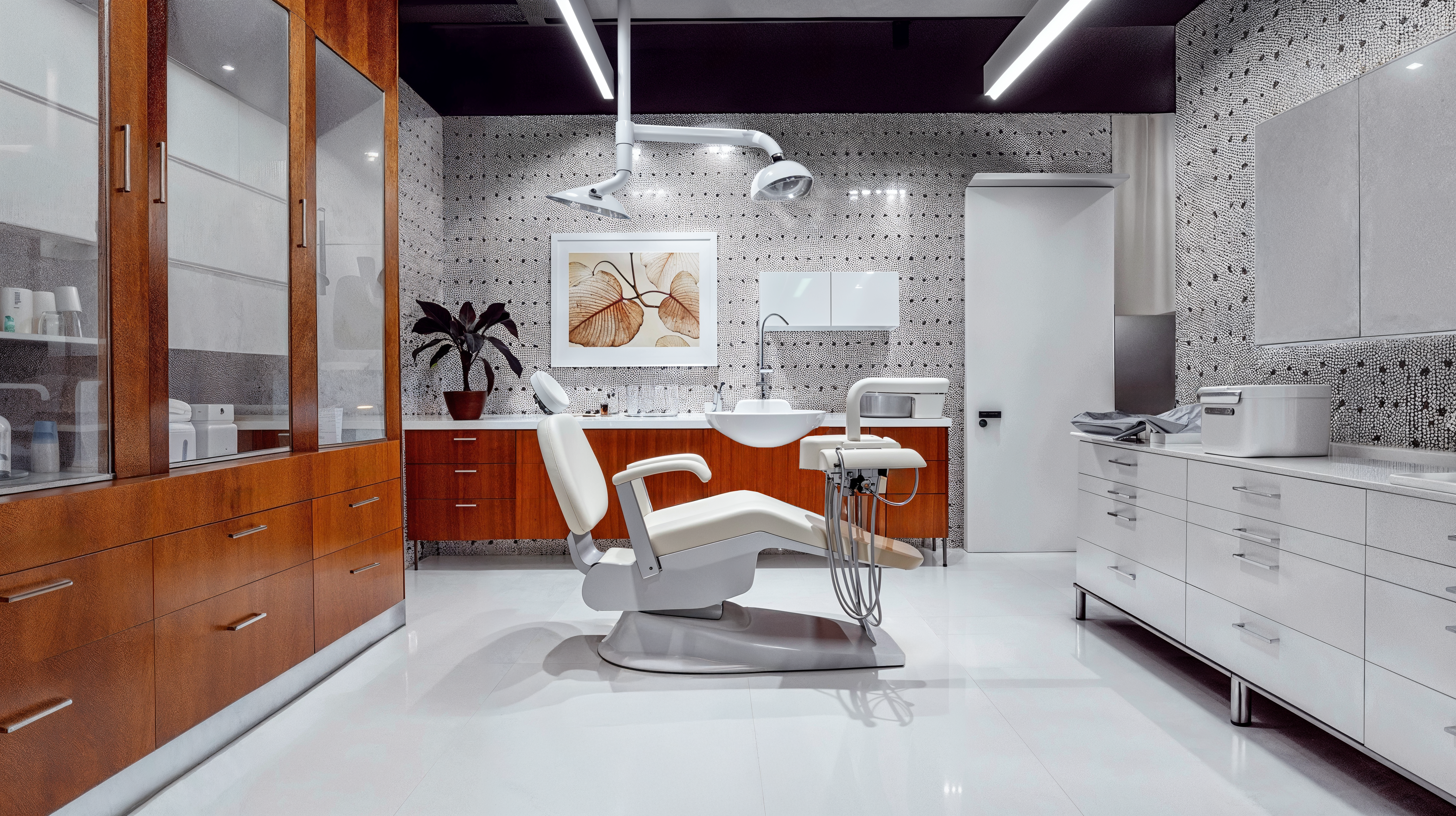 Mid-century modern dental offices with a contemporary dental chair, overhead lighting, sterile white tile flooring, wood cabinetry balanced with white cabinetry, and subtle black and white patterned wallpaper.