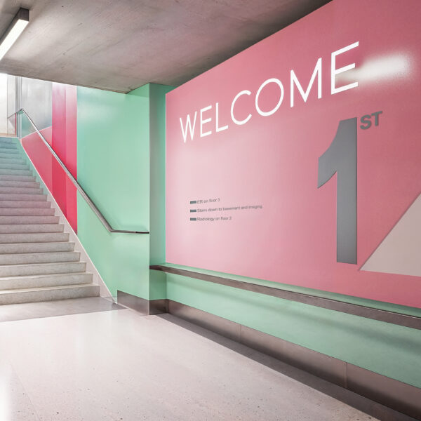 A complex medical center which usings wayfinding to help visitors and staff navigate throughout the building. Directions in bright colors running along the walls help people orient themselves in the space.