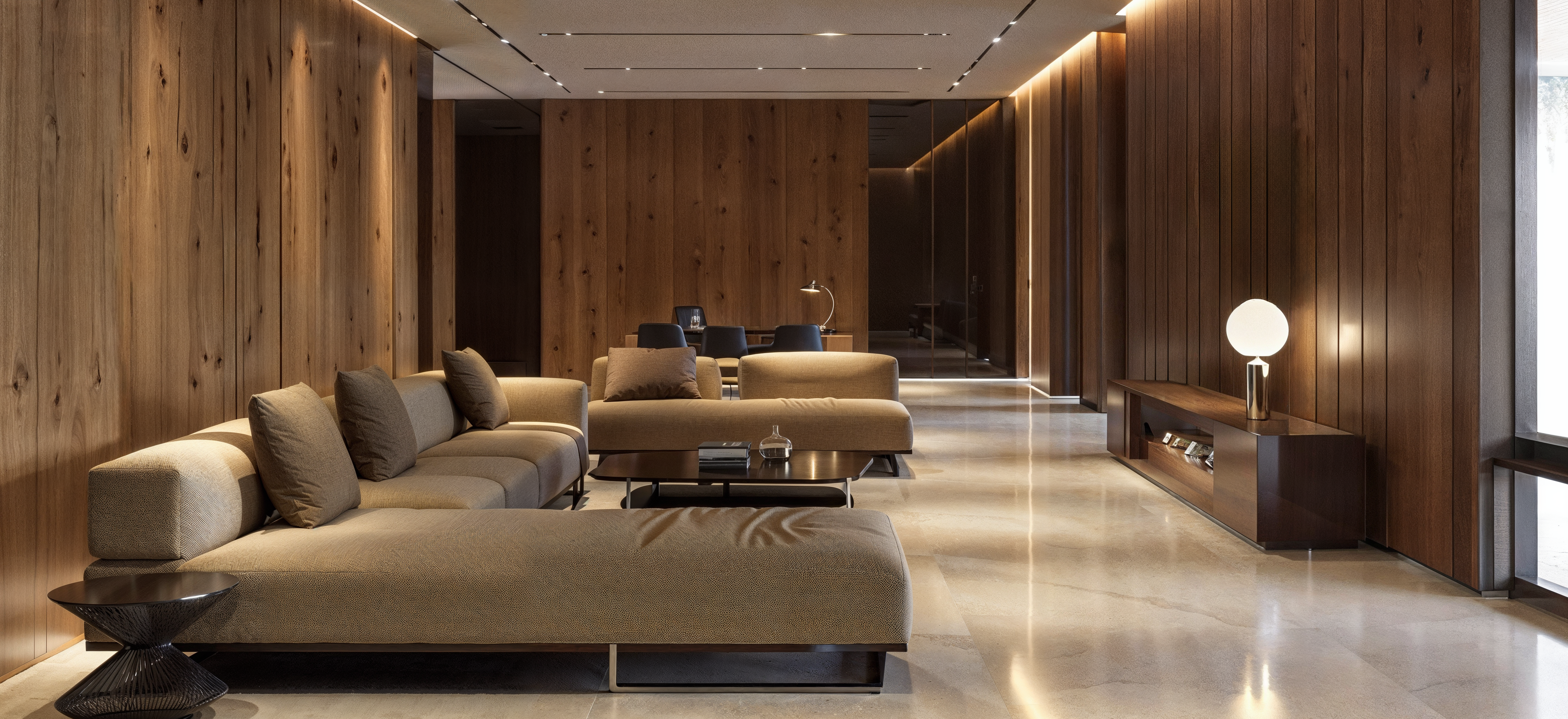 A hotel lounge with wood paneling on the walls in a contemporary design with tan couches and light beige tile floors.