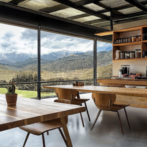 Peruvian Andean Design inspired workplace with communal wood tables and chairs, floor to ceiling windows.