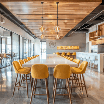 A Scandinavian workplace cafeteria with plush yellow seating, wooden shelving, and natural stone flooring.