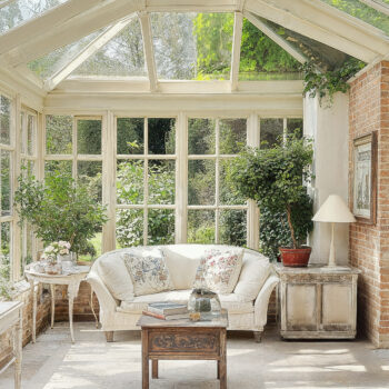 A Victorian conservatory inspired living area with natural lighting, plush furniture, and rustic wallcoverings.