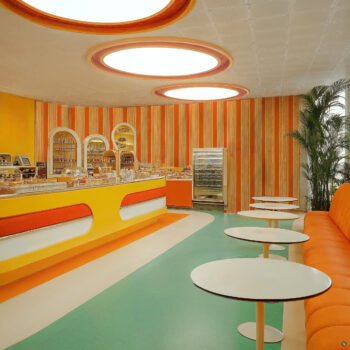 A Googie candy shop interior with colorful wall paneling, teal tile flooring, and silver countertops.