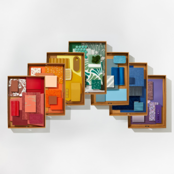 A flatlay image of boxed colorful textiles, stone, wallpaper, and materials.
