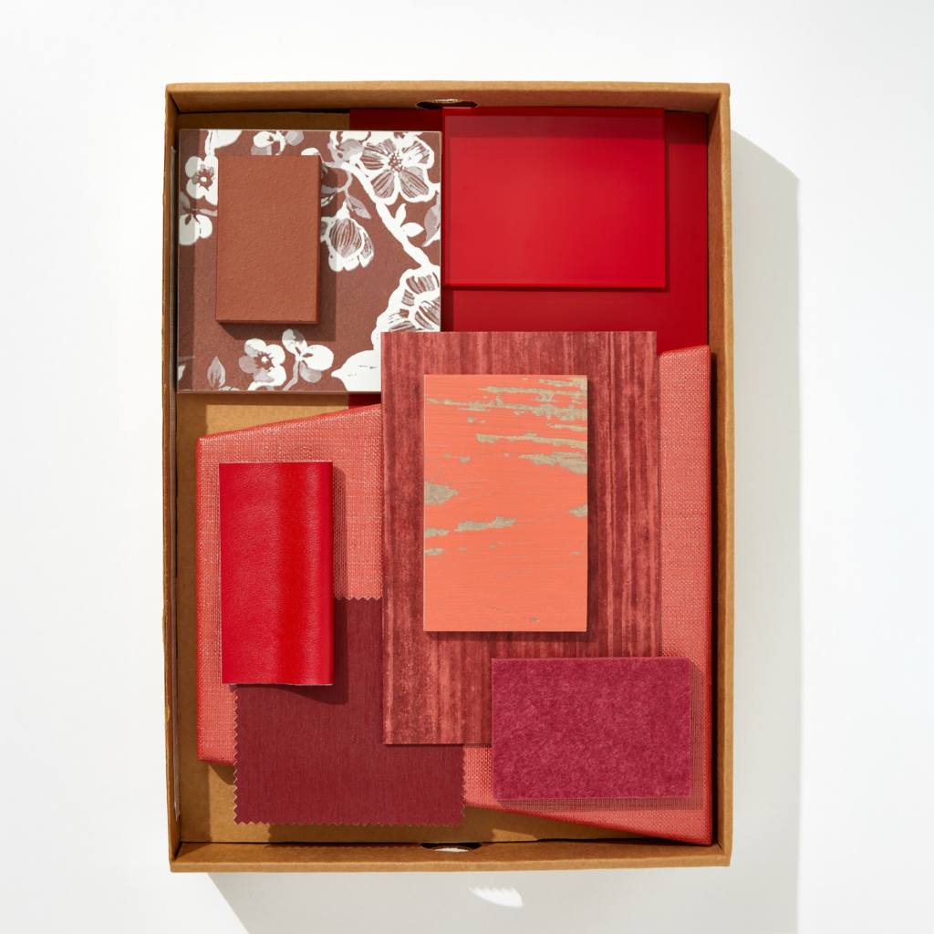 A flatlay image of boxed red textiles, stone, wallpaper, and materials.