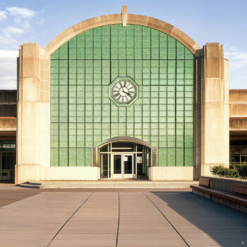 An art deco bus terminal with concrete exteriors, brick walkways, and emerald green finishes.