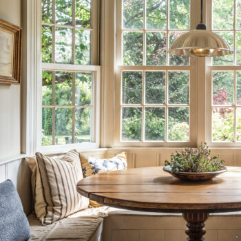 Farmhouse breakfast nook with light wood wall paneling, wood table, built in banquette.