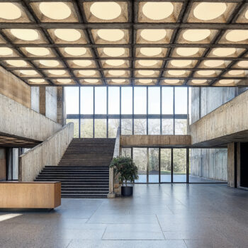 A brutalist data center with concrete walls, large windows, and wooden wall paneling.