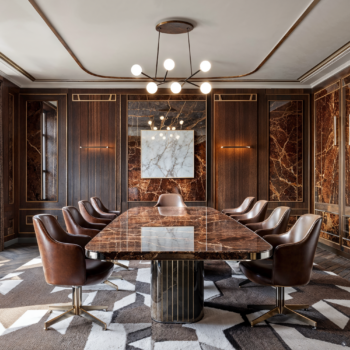 An art deco boardroom with leather seating, wood paneling, decadent chandeliers.