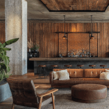 A hospitality space with wooden wall panels, leather upholstered furniture, and exposed concrete beams.