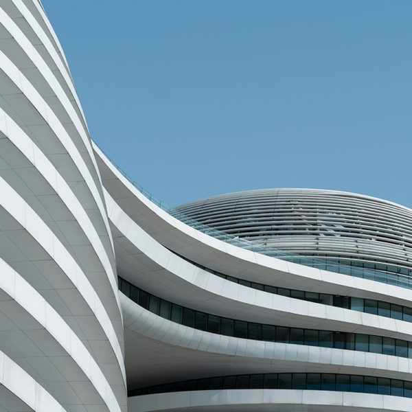 Modern architecture, a modern high-rise building with curved lines and white exterior walls, a closeup of the facade against a blue sky