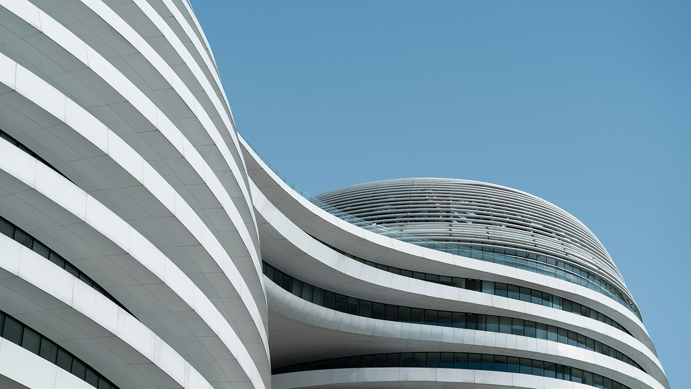 Modern architecture, a modern high-rise building with curved lines and white exterior walls, a closeup of the facade against a blue sky