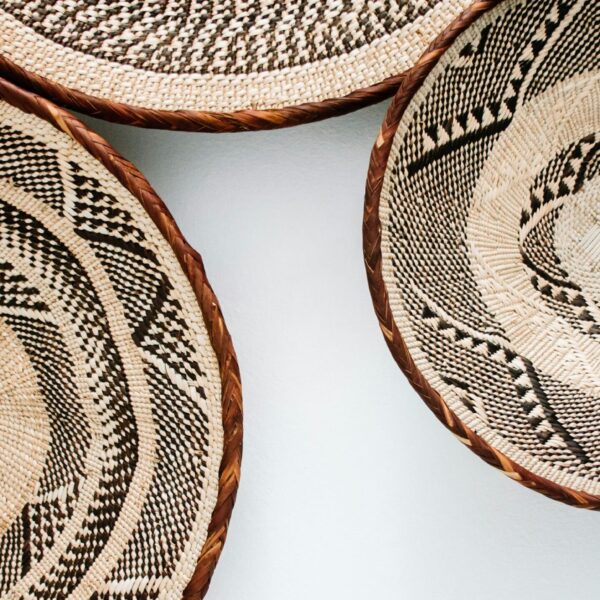 A closeup of three woven baskets with geometric patterns, arranged on a white background. The basket designs feature intricate black and brown designs that create visual interest and depth.