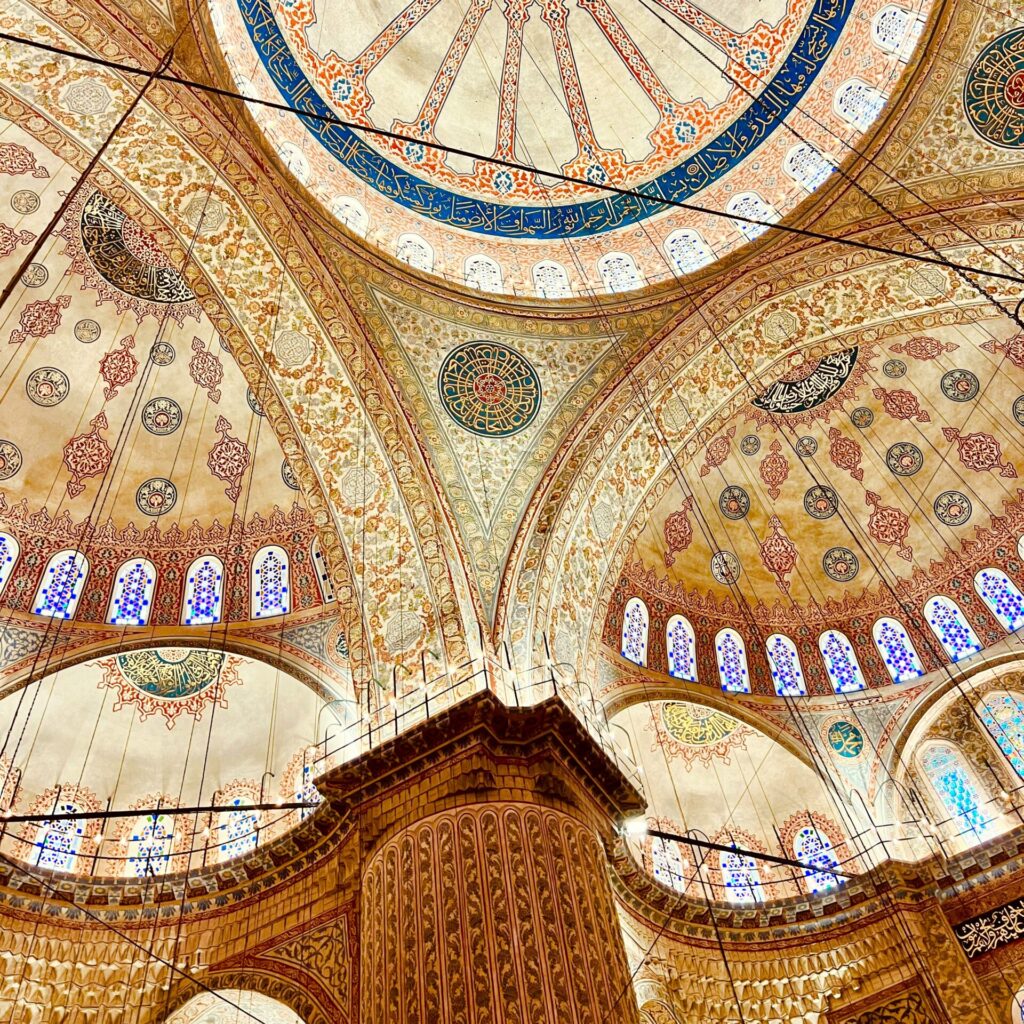 A closeup shot of the intricate domes and archways ceiling inside The Blue Mosque, showcasing its colorful mosaic tiles and ornate patterns.