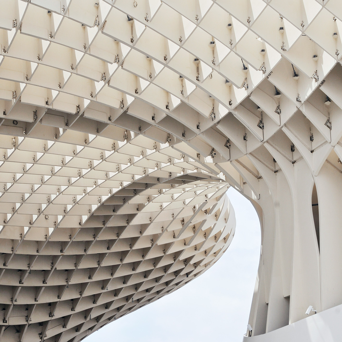 A close up detail of white architectural wood structure, Setas de Sevilla, in the shape of arches, covered with small hexagonal shapes made from different materials, located in Seville, Spain.