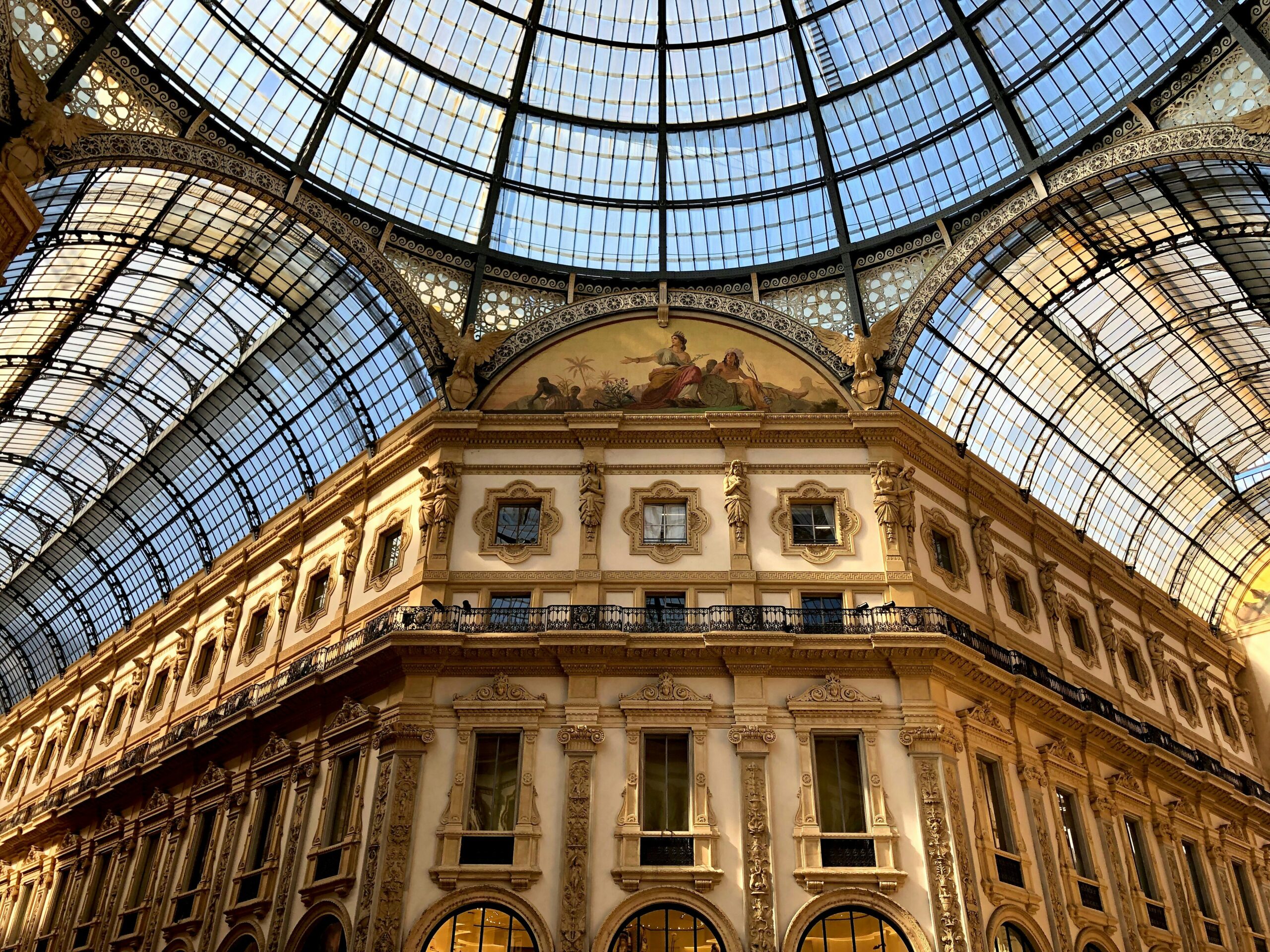 Photograph of Galleria Vittorio Emanuele II, Milan, Metropolitan City of Milan, Italy. Looking up at the building and the glass ceilings.