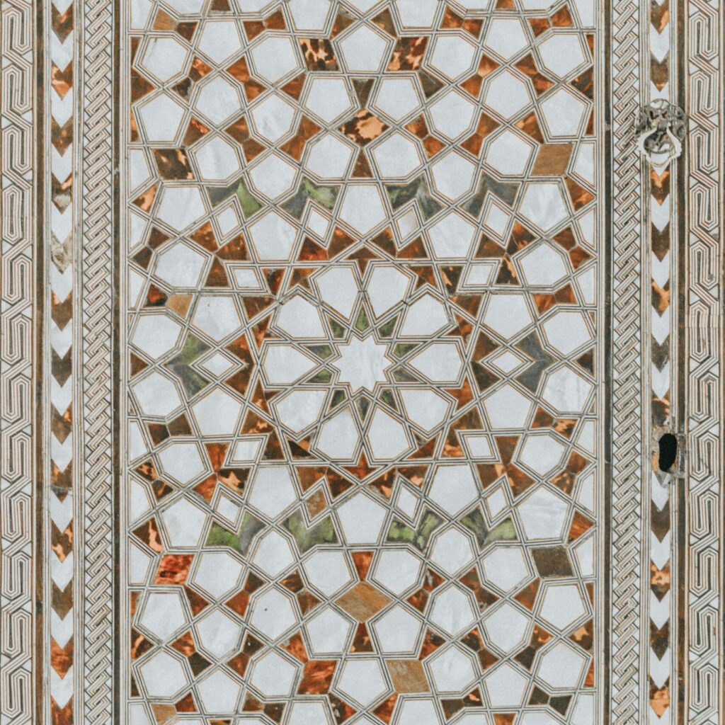 A closeup of an arabesque design geometric pattern, showcasing the intricate designs and patterns inspired by Islamic architecture. The design incorporates white, green and orange.