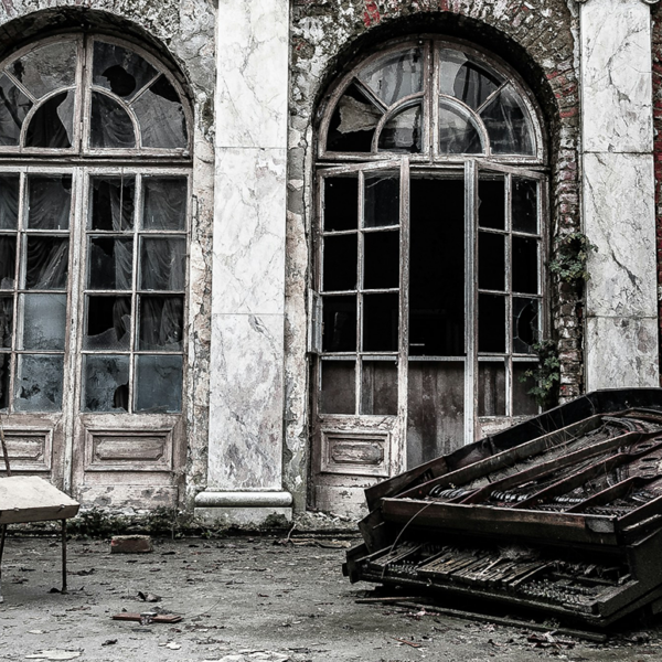 An abandoned palace with broken windows and a destroyed grand piano in the foreground.