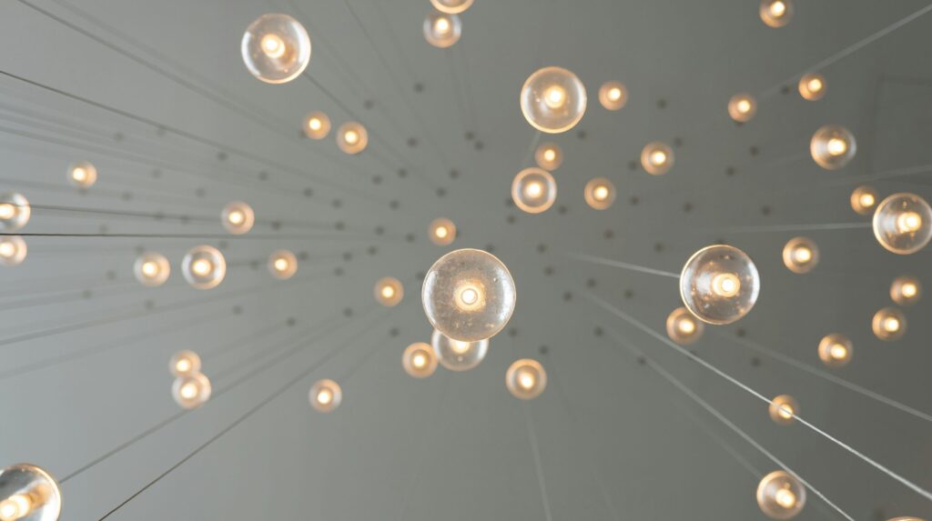 Shot from underneath looking up at a ceiling of clear globe pendant lights hanging down against a solid white background.