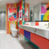 Pop Art Bathroom with neutral colored tile, stone sink with colorful wallcovering in bold, vibrant colors and geometric patterns.