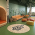 Playrooms in Pediatric Healthcare in a nature inspired theme with large fake trees in growing out of the floor, brightly colored green floor, with seating areas in shades of red, orange and yellow providing different areas for play.