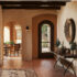 Native American Pueblo Design residential home hallway, with tile floors, archway doors, wood accents with a view from the hallway looking at the front door on the right and the dining room on the left.