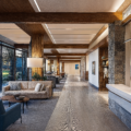 Argentinian Estancia Design healthcare lobby with stone detail, wooden beams, large windows, neutral palette.
