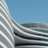 Modern architecture, a modern high-rise building with curved lines and white exterior walls, a closeup of the facade against a blue sky