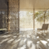 Image of a minimalist interior with an open floor. The room is bathed in natural light with dividers creating light and shadow. A single chair sits in the room.