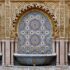 A courtyard designed in arabesque patterned tile with a decorative fountain in the middle.