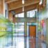 Sustainable high school interior with big windows, wood paneling on the ceiling, and bright lockers.